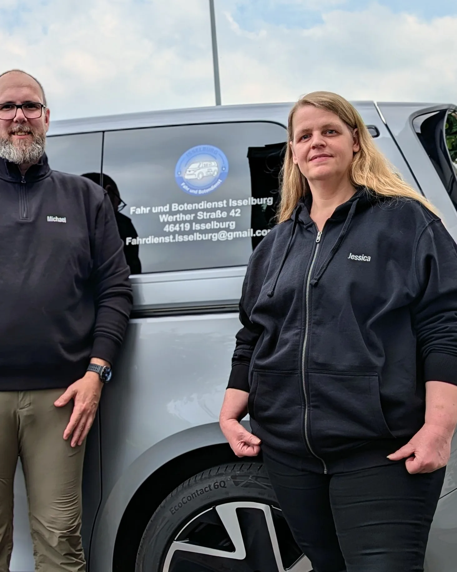 Michael Schmidt und Jessica Schmidt-Köpke stehen vor dem beschrifteten Elektrofahrzeug des Fahrdienstes