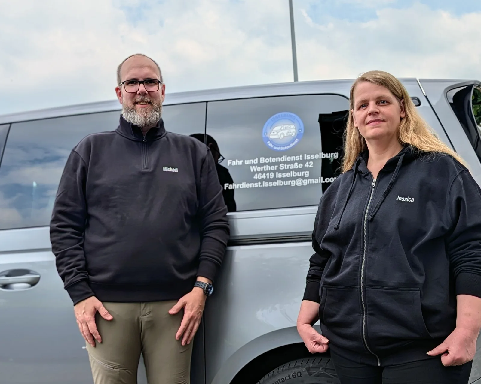 Michael Schmidt und Jessica Schmidt-Köpke stehen vor dem beschrifteten Elektrofahrzeug des Fahrdienstes